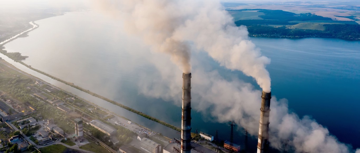 Aerial view of coal power plant high pipes with black smoke moving up polluting atmosphere at sunrise.
